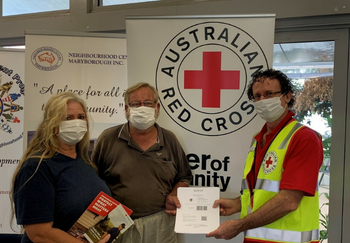 A Red Cross staff member in Maryborough handing over grocery vouchers from GIVIT to a husband and wife.