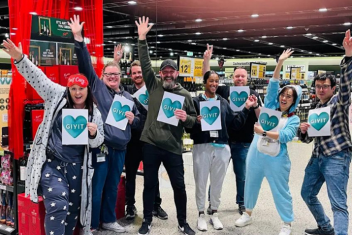 Dan's staff dressed in their PJ's, holding GIVIT heart signs in the DAN's store.